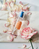 Nuria Defend Essence - bottle laying on flower petals