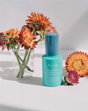Nuria Hydrate Moisture Replenishing Serum - bottle on counter with ingredient, everlasting flower, surrounding