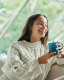 Nuria Hydrate Nourishing Under-Eye Masks - woman smiling and holding from mug while wearing under-eye masks