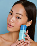 Nuria Hydrate Refreshing Micellar Water - woman holding bottle up to her face