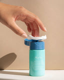 Nuria Hydrate Refreshing Micellar Water - woman applying cotton pad to pump applicator of open bottle