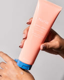 Nuria Defend Gentle Exfoliator - product being dispensed onto back of hand