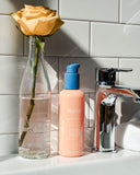 Nuria Defend Cleanser - bottle on sink with flower