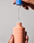 Nuria Defend Skin Restoring Serum - close-up of bottle with dropper removed and held over top of bottle to reveal clear serum