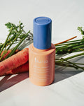 Defend Skin Restoring Serum - bottle on counter with carrots in background