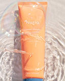 Nuria Defend Gentle Exfoliator - bottle underwater with ripples and sunlight