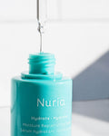 Nuria Hydrate Moisture Replenishing Serum - bottle with dropper held above it, showing clear serum dripping back into bottle