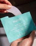 Nuria Hydrate Nourishing Under-Eye Masks - person removing one pair of under-eye masks from opened envelope