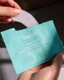 Nuria Hydrate Nourishing Under-Eye Masks - person removing one pair of under-eye masks from opened envelope