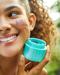 Nuria Hydrate Revitalizing Jelly Night Treatment - woman smiling with jelly applied to cheek and holding open jar