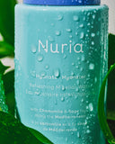 Nuria Hydrate Refreshing Micellar Water - bottle with droplets resting amongst green leaves