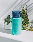 Nuria Hydrate Refreshing Micellar Water - bottle on countertop with ingredients - chamomile and sage